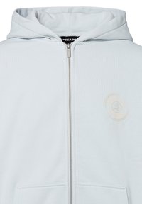 Felpa con zip di colore azzurro chiaro, realizzata in tessuto morbido. Presenta una chiusura con zip frontale e una stampa logo discreta sul lato sinistro del petto.