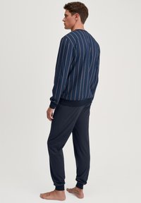 Marine gestreepte sweatshirt met contrasterende verticale lijnen, gecombineerd met effen donker marineblauwe broek. Katoenmix stof; ontspannen pasvorm, geribbelde manchetten.