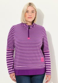 Lila und lavendelfarbene gestreifte Zip-Up-Jacke mit Stehkragen und pinkem Akzent-Patch. Lange Ärmel und weicher Stoff.