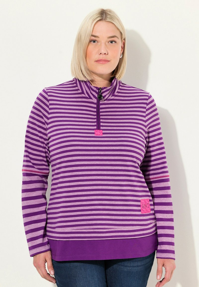 Lila und lavendelfarbene gestreifte Zip-Up-Jacke mit Stehkragen und pinkem Akzent-Patch. Lange Ärmel und weicher Stoff.