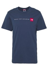 Camiseta de algodón azul marino con mangas cortas, cuello redondo y texto blanco que dice "NUNCA DEJES DE EXPLORAR" encima de un parche de logo rojo.