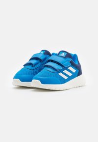 Chaussures de sport bleues avec une tige en mesh, deux bandes velcro, des accents blancs et une épaisse semelle en caoutchouc blanc. Présente le logo Adidas sur la languette.