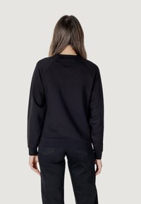 Felpa nera con scollatura tonda e maniche raglan. Presenta un tessuto morbido e una finitura leggermente texturizzata. Senza loghi o motivi visibili.