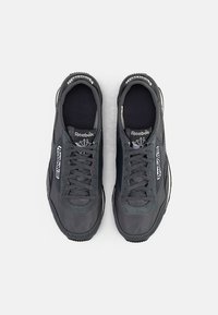 Čierne atletické tenisky s hladkým syntetickým zvrškom, sieťovinovým detailom, plochými šnúrkami a textúrovanou gumovou podrážkou. Viditeľná značka Reebok.