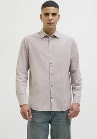 Camisa de manga larga de color beige claro, hecha de tejido texturizado, con un cuello clásico y cierre de botones en la parte delantera, con puños abotonados.