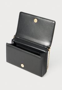 Black leather clutch bag with magnetic gold button closure, open flap, and gold chain strap against a neutral background.