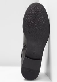 Semelle de botte noire avec un motif floral texturé, taille 37. Dotée de bords lisses et d'un léger talon, conçue pour l'adhérence et la stabilité.