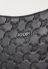 Borsa in pelle nera con superficie testurizzata e motivi in rilievo. Logo del marchio "JOOP!" in argento al centro della parte anteriore. Bordo liscio.