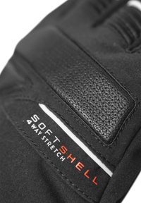 Black glove featuring a textured leather patch, white stitching, and "SOFT SHELL 4 WAY STRETCH" label in red and white.