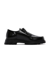 Zapatos de cuero negro con un acabado pulido, punta redondeada y una suela de goma gruesa y resistente con pequeños tacos para tracción.