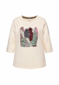Cremfarbene Bluse mit Dreiviertelärmeln, die mit strukturierten Stickereien in Grün, Burgunder und Grau verziert ist, angeordnet in einem geschichteten Design.
