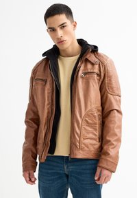 Chaqueta de cuero marrón con capucha negra, presenta acentos de acolchado vertical, bolsillos con cremallera y un diseño ligeramente ajustado.