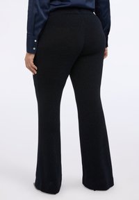 Černé rozšířené kalhoty s jemným leskem, s hladkou texturou a elastickým pasem, navržené pro přiléhavý siluetu.