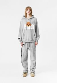 Sudadera gris con un diseño de perro de dibujos animados y texto grande en blanco, combinada con pantalones grises a juego que cuentan con rayas laterales y bolsillos.