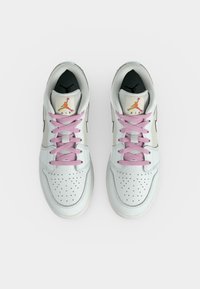 Λευκά sneakers Air Jordan με ροζ κορδόνια και διάτρητα τμήματα στα δάχτυλα, από πάνω σε λευκό φόντο.