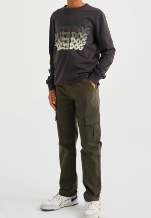 Tummanharmaa pitkähihaine paita, jossa on erivärisiä "Salty Dog" -grafiikoita, yhdistettynä oliivinvihreisiin cargo-housuihin ja valkoisiin tennareihin.