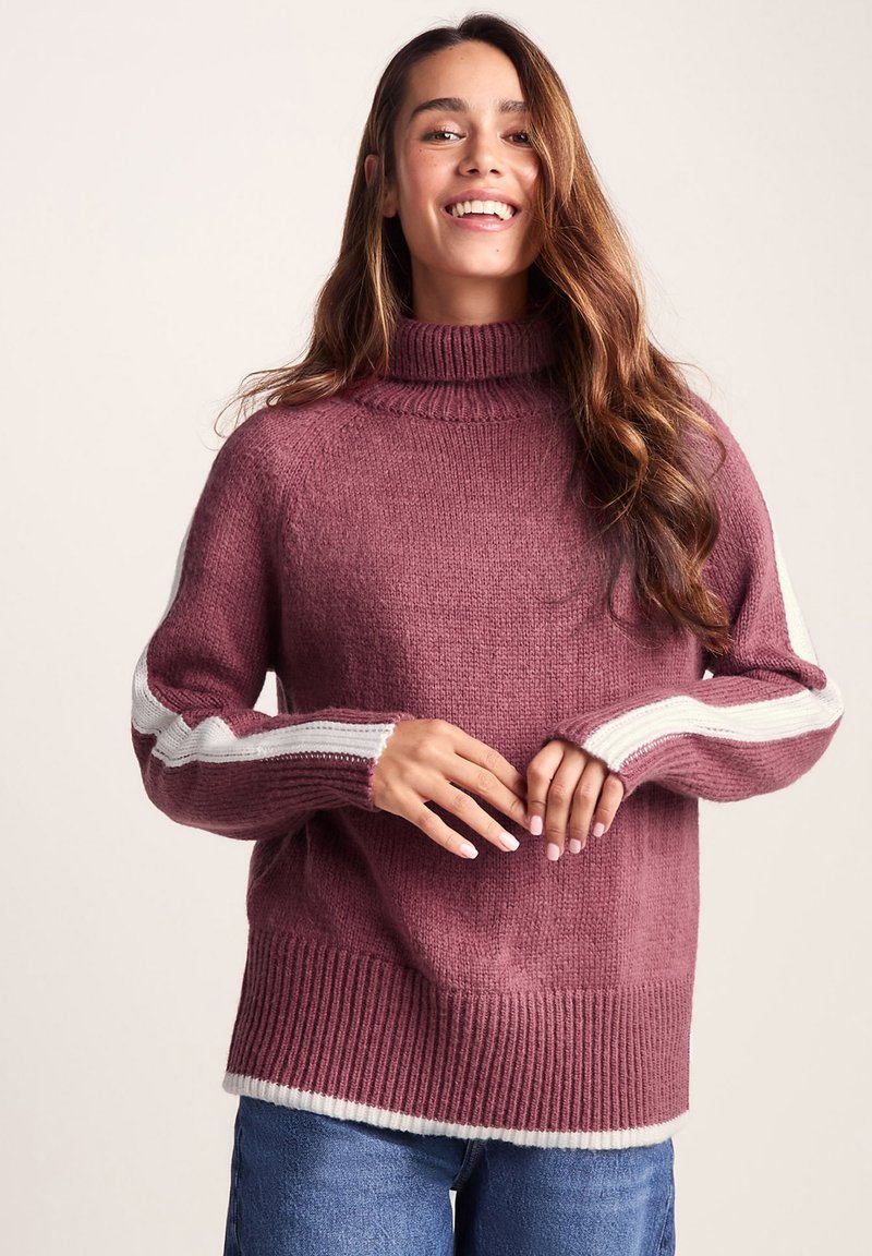 Purple knit sweater with a turtleneck, ribbed hem, and long sleeves featuring white diagonal stripes along the arms. Smooth texture.