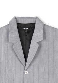 Blazer gris en tissu léger, avec des rayures verticales, un col cranté et une fermeture à un bouton. Étiquette DKNY visible à l'intérieur.