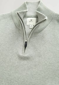Suéter de media cremallera de color gris claro con canalé y cuello levantado, con tirador de cremallera visible y etiqueta de la marca "NEXT" dentro del cuello.