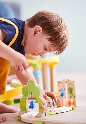 Wooden toy train set with green arch, blue bell, and colorful animal figures. Features curved tracks and playful designs on pieces.