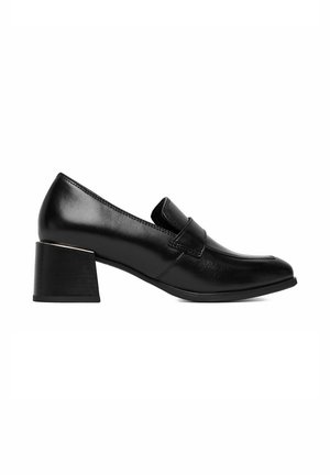 Mocasín de cuero negro para mujer con tacón grueso de altura media y una correa decorativa en la parte superior, fotografiado sobre un fondo blanco.