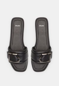 Melni slides sandalī ar platām siksnām un sudraba sprādzi, gluda ādas tekstūra un šūtas detaļas ap malām.
