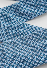 Blauwe stof met een herhalend cirkelpatroon met witte en lichtblauwe accenten. Soepele textuur, op maat gemaakt ontwerp geschikt voor kleding.