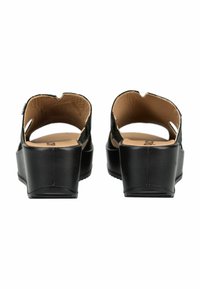 Sandalias de cuña negras con partes traseras abiertas y plantillas acolchadas color beige, mostradas desde la vista trasera sobre un fondo blanco.