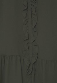 Vestido verde oscuro con un pliegue en la parte frontal, que presenta una textura suave y una cintura fruncida. Diseño sencillo sin patrones ni acentos adicionales.