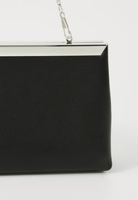 Black leather clutch bag with a textured surface. Features a silver metal frame and a short chain handle for carrying.