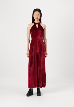 Bordeaux mouwloze jumpsuit met een sleutelgaatje-halslijn, gemaakt van zacht velours materiaal, met brede broekspijpen en een gladde textuur.