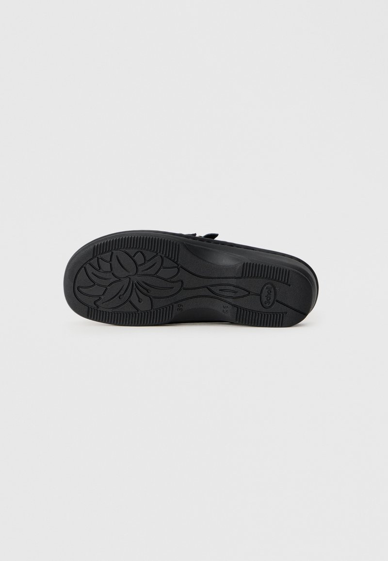 Semelle de chaussure noire avec un motif de grip texturé et un design floral. Présente une forme arrondie et des bords droits en matériau en caoutchouc robuste.