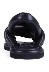 Sandalia deslizante de cuero negro con parte superior acolchada y suave y suela de goma plana. Diseño sin costuras, sin hardware visible ni acentos.