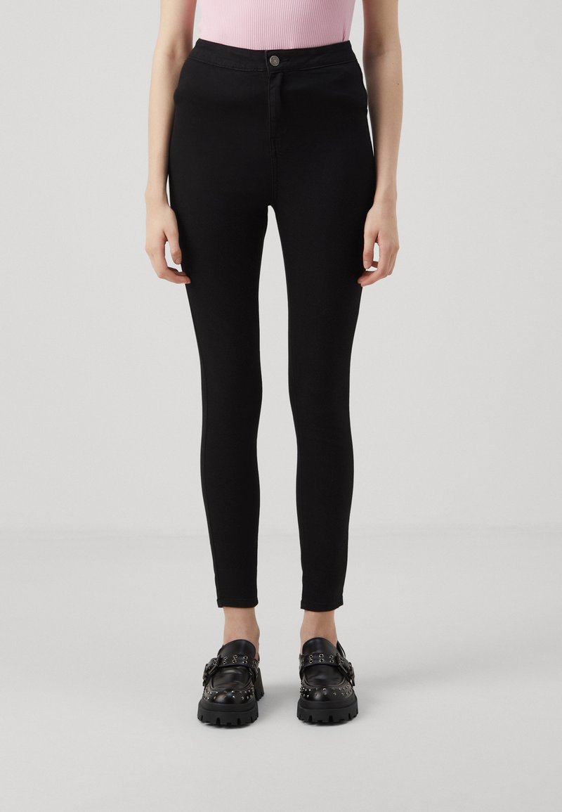 Jeans skinny negros con cintura alta, hechos de denim elástico. Presentan un cierre frontal con botón y un diseño ajustado y suave.