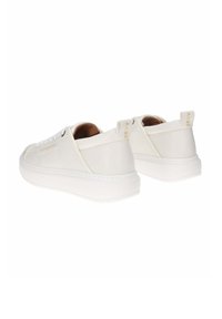 Des baskets blanches en cuir présentent une finition lisse, un bout rond et une semelle rembourrée. Elles incluent des accents dorés et des tirettes en tissu au niveau du talon.