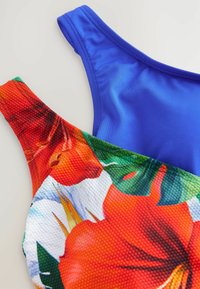 Deux bretelles de maillot de bain : l'une est bleu uni avec une texture lisse, l'autre présente un imprimé floral coloré avec une surface texturée.