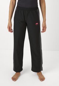 Sorte stretchy treningsbukser med elastisk liv, sidelommer og en rosa logo på venstre lår, med en rett snittdesign.