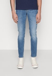 Ljusblå denimjeans med smal passform, med lätt tvätt, och matchade med vita högskurna sneakers.