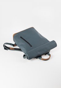 Grauer Rolltop-Rucksack aus wasserdichtem Material, mit einem braunen Lederakzent, einer Vorderseite mit Reißverschluss und verstellbaren Trägern.