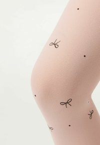 Ljust rosa strumpbyxor gjorda av texturerat tyg, med ett mönster av små svarta bågar och prickar fördelade över ytan.