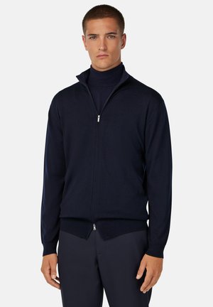 Cardigan zip-up navy realizzato in tessuto morbido, presenta un colletto alto e polsini a coste. Vestibilità slim con dettagli minimi.