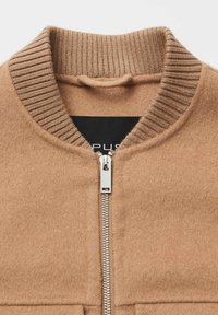 Giacca bomber in lana color cognac con colletto a costine, cerniera argentata e tessuto texturizzato. Etichetta visibile all'interno della zona del collo.