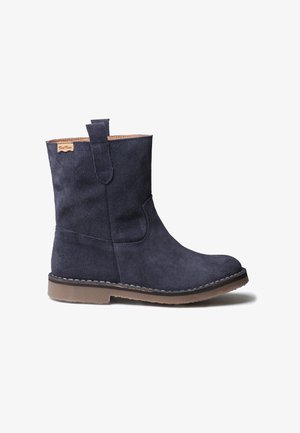 Marineblauwe suede laars tot halverwege het kalf met een tan zool, trek lus en gestikte details, weergegeven in zijprofiel op een witte achtergrond.