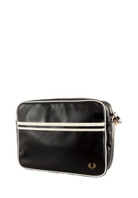 Borsa sintetica nera con strisce bianche, forma rettangolare, chiusura con zip, tracolla regolabile e dettaglio del logo dorato sulla parte frontale.