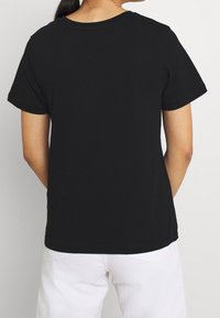 Černé triko s krátkým rukávem a kulatým výstřihem. Vyrobeno z hladké bavlněné směsi. Jednoduchý design, žádné viditelné logo nebo vzory.