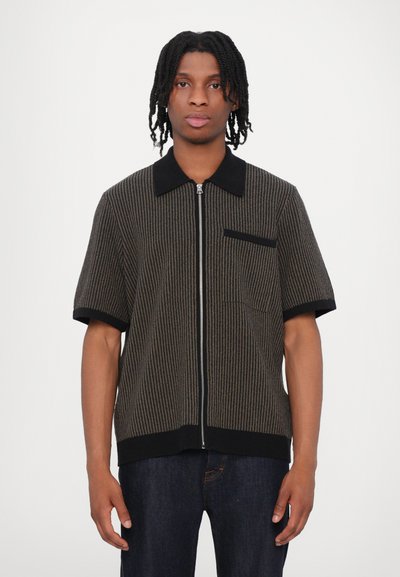 Chemise zippée en tricot à manches courtes noire et marron avec des rayures verticales, un col et une poche poitrine avec un appliqué noir contrastant.