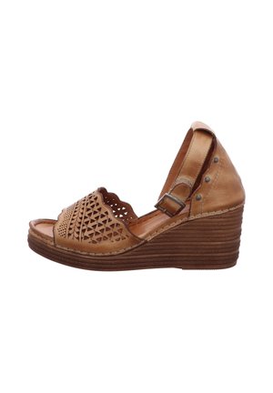 Tan leather wedge sandal with cut-out geometric patterns, a scalloped toe design, ankle strap, and a textured, ridged sole.