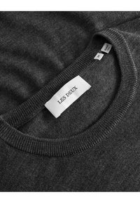 Kohle-grauer Pullover mit Rundhalsausschnitt und geripptem Kragen. Das Etikett zeigt den Markennamen "LES DEUX" und die Größe "M". Weiches, strukturiertes Material.