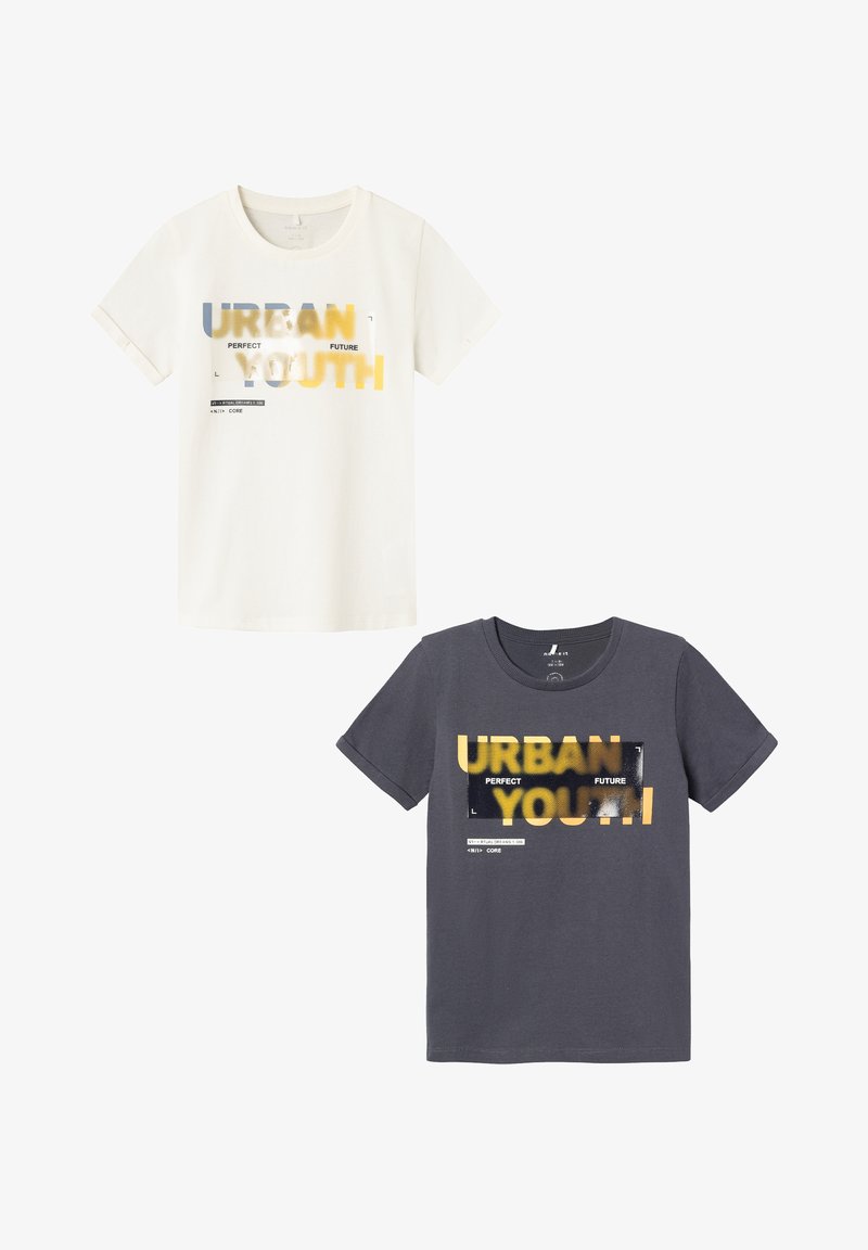 Zwei T-Shirts: eines in Creme mit gelbem und blauem Text, das andere in Dunkelgrau mit gelbem und schwarzem Text. Beide haben kurze Ärmel und einen lässigen Schnitt.