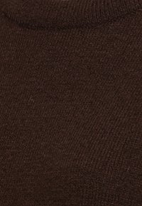 Brun stickad tyg med en fin textur och en slät yta. Materialet har lätt varierande nyanser.